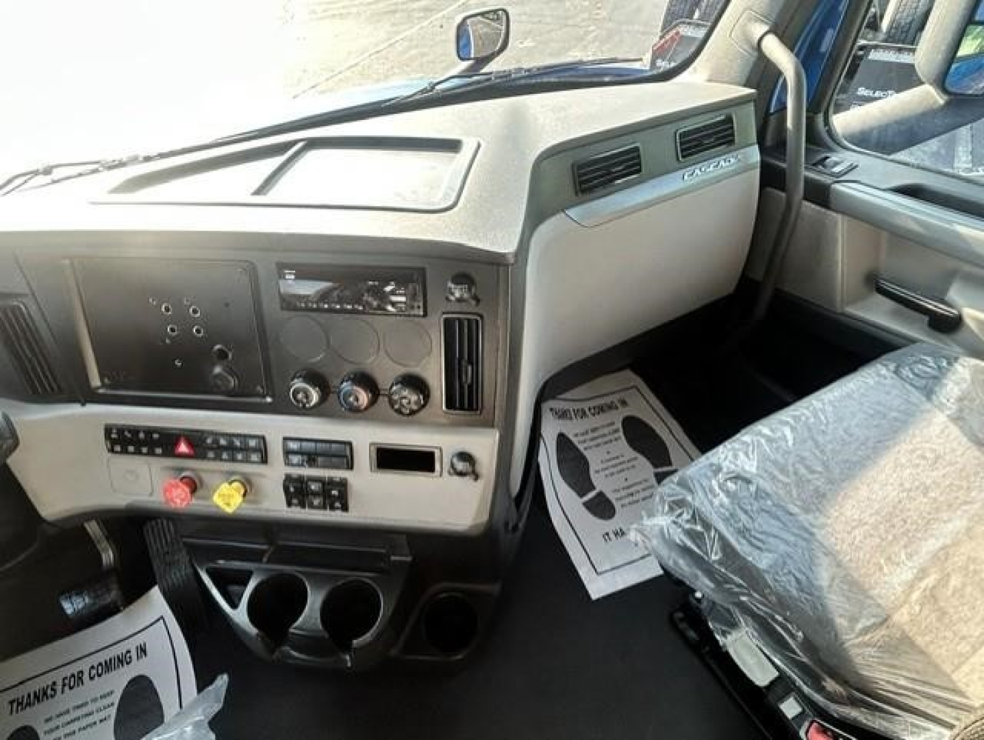 Cab interior of 2021 Freightliner Cascadia 126 with steering wheel, dashboard controls, and front seats visible