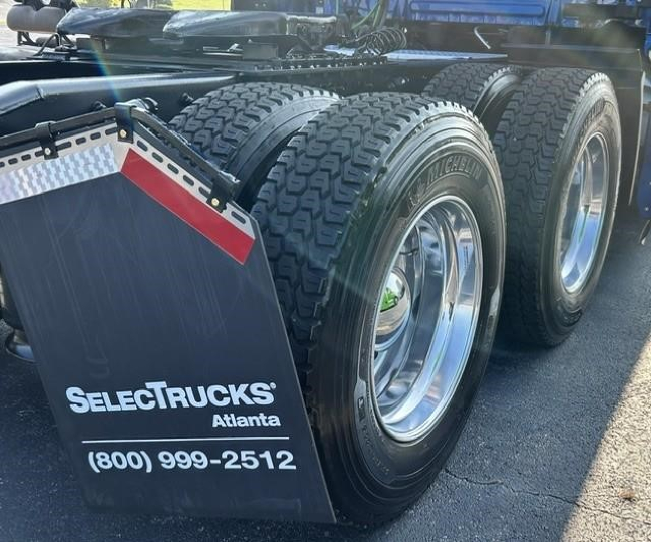 Triple-axle Freightliner Cascadia rear view showing fuel tanks and wheels, Select Trucks Atlanta mudflap with phone number.