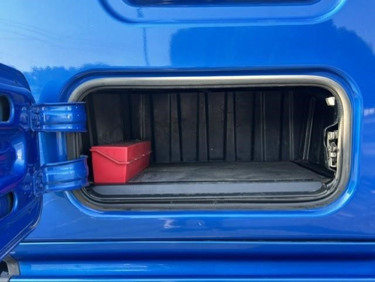 Freightliner Cascadia 126 fuel/maintenance hatch open showing a small red toolbox inside the side compartment.