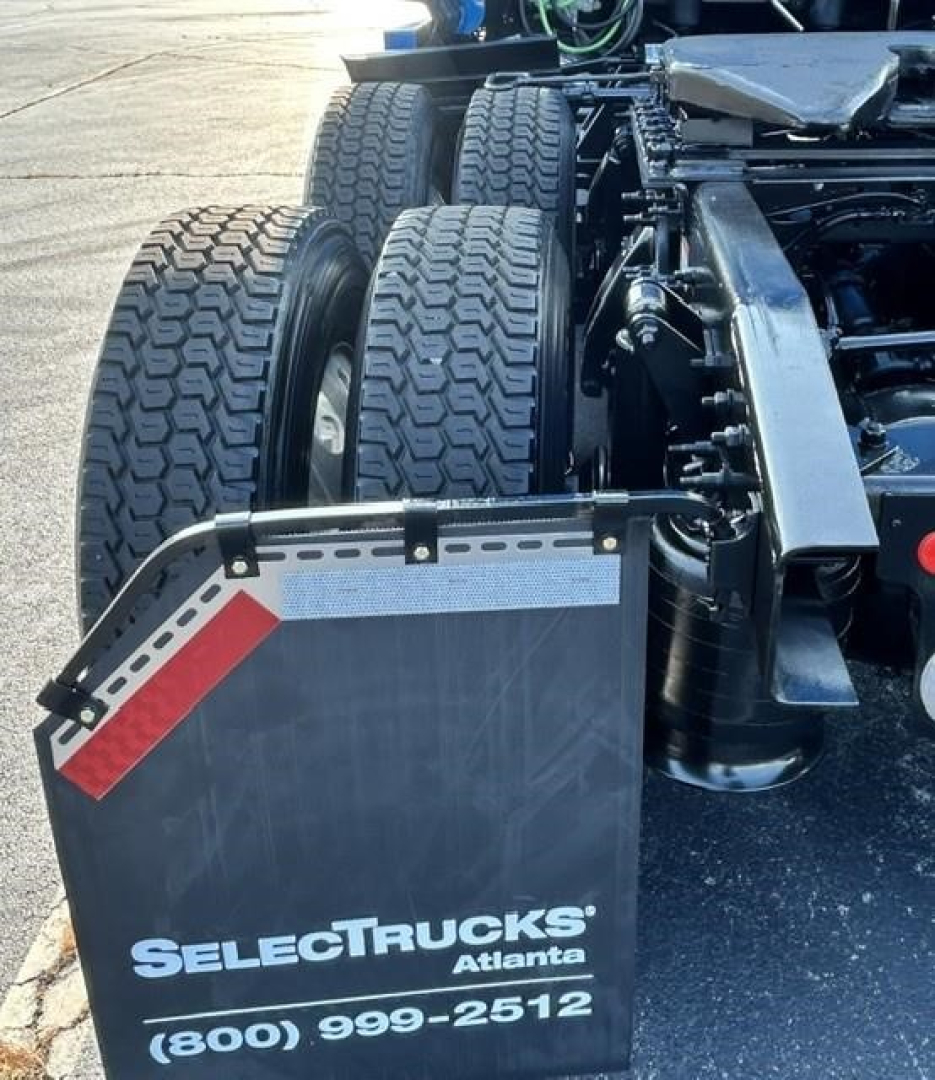 SelectTrucks Atlanta chassis with dual rear axles and fifth wheel mount. Visible: triple rear tires, metal fenders, and hydraulic components.