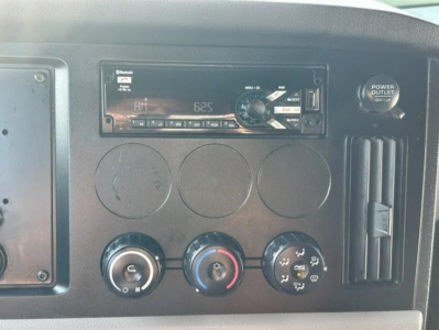 Dashboard area of a 2021 Freightliner Cascadia 126 showing an aftermarket stereo head unit, climate controls, and power outlet.