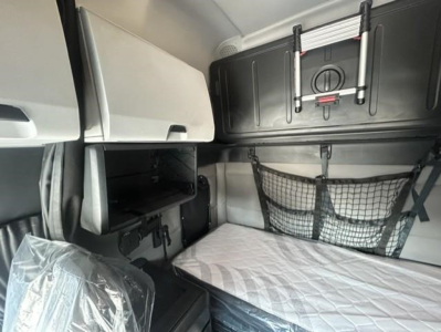 Cascadia sleeper cab interior showing bunk area with net storage, overhead cabinet, and window shade.
