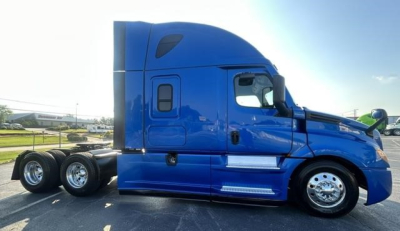 Truck side profile showing a blue Freightliner Cascadia 126 sleeper cab tractor with dual rear axles, chrome wheels, and aerodynamic body lines.