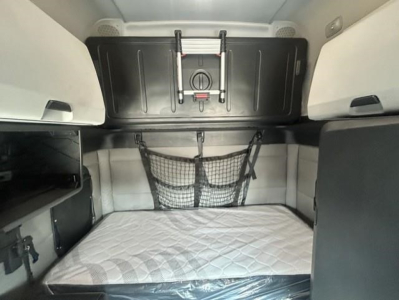 Freightliner Cascadia sleeper cab interior showing bunk bed area with storage nets and shelves.