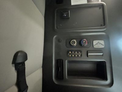 Trucking cab interior panel showing climate control dials, storage pocket, and small switch panel inside a Freightliner Cascadia 126.