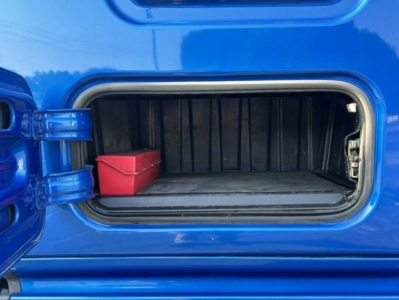 Freightliner Cascadia 126 fuel/maintenance hatch open showing a small red toolbox inside the side compartment.