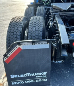 SelectTrucks Atlanta chassis with dual rear axles and fifth wheel mount. Visible: triple rear tires, metal fenders, and hydraulic components.
