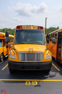 Front view of a yellow Freightliner Thomas Saf-T-Liner school bus with 'SCHOOL BUS' sign on top, number 323 on hood, and grille visible.
