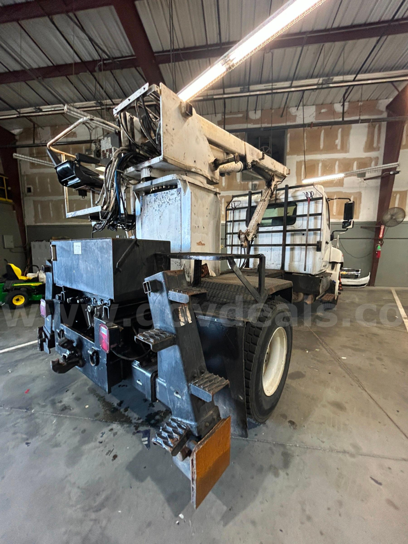 Rear view of a Hino boom truck with hydraulic arm raised, showing winch, control boxes, and rear tires.