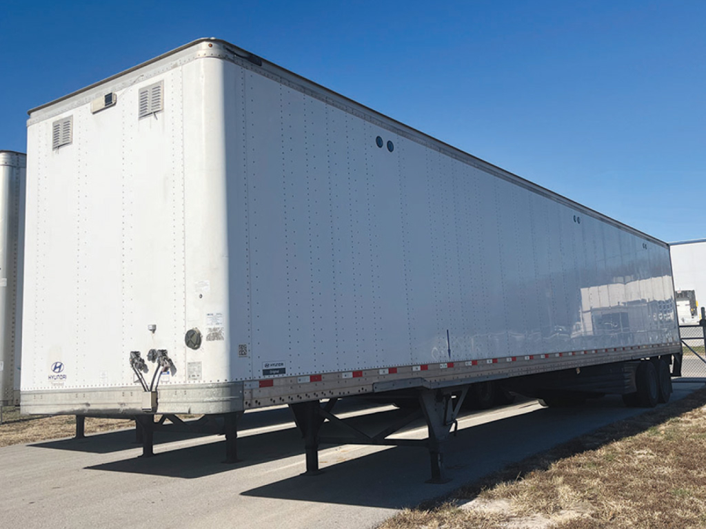 Trailer body showing side and rear, aluminum exterior, dual axles, undercarriage and landing gear, no visible branding text.