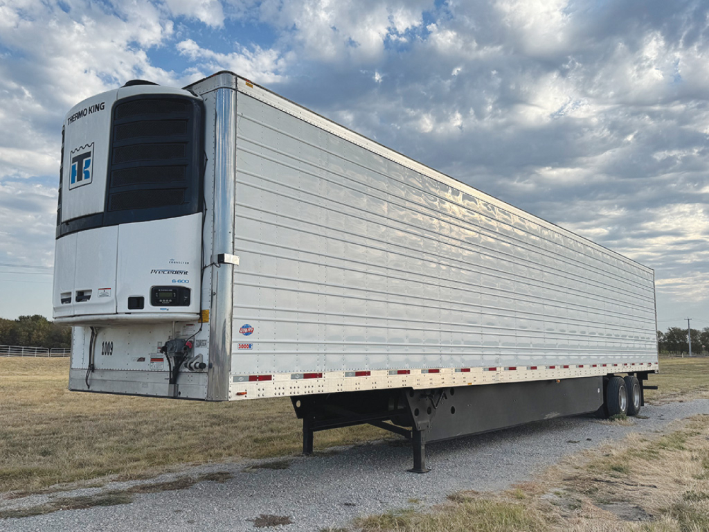 Utility 3000R reefer trailer with Thermo King unit at front, side aluminum panels, landing gear down, in a gravel lot.