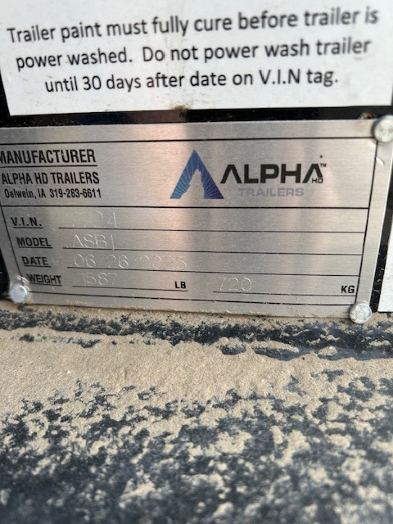 Trailer manufacturer plate showing Alpha Trailers logo with VIN, model ASB1, date, weight and other specs. Upper text mentions wash instructions for trailer.