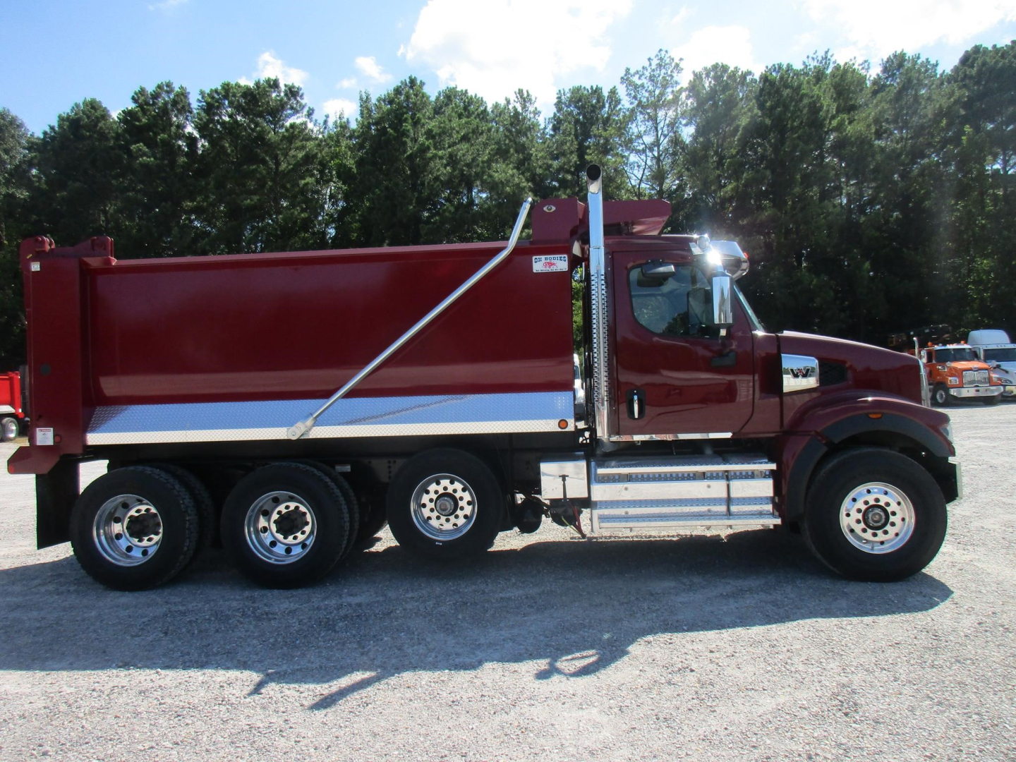 Western Star 49X dump truck side view showing red dump body, chrome fuel tanks, and multiple rear axles.