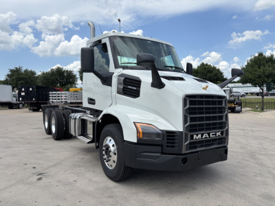 Mack AN64 dump truck front-left view in bright day with white cab and black grille; visible side mirrors; large exhaust stacks; no visible text on cab. 