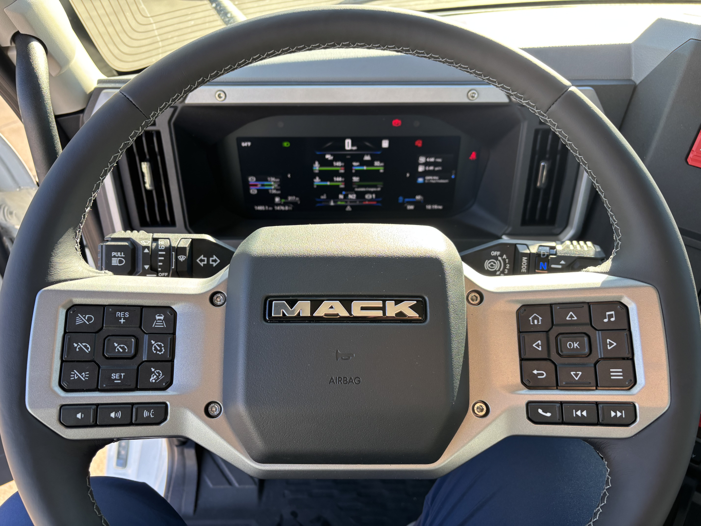 Mack PR64T dashboard steering wheel view showing digital instrument cluster and steering wheel controls.