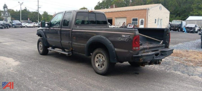 2007 Ford F-250 Super Duty pickup truck with extended cab and single rear wheel, black/gray, viewed from rear left in a lot with tailgate down.