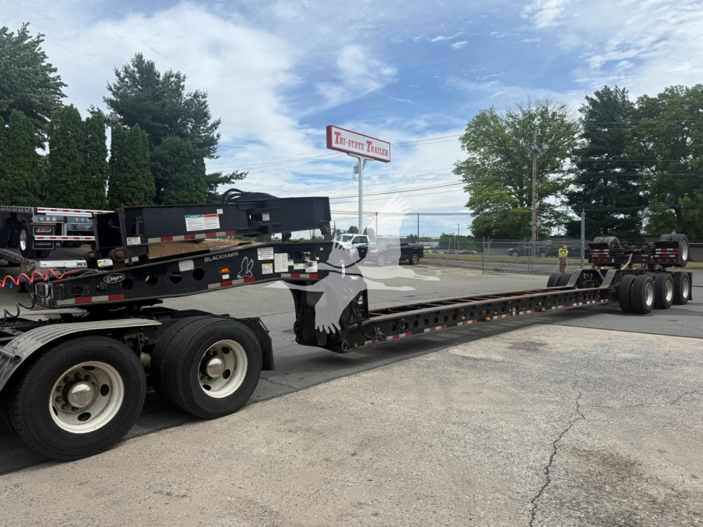2014 Etnyre beam lowboy trailer showing long flat deck with multiple axles and loading equipment in background.