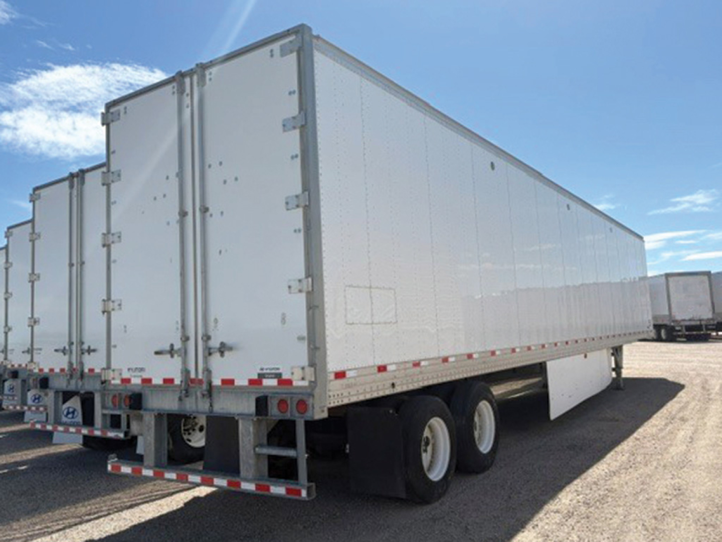 Hyundai Translead trailer in a lot, white tandem-axle dry van with rear and side doors, visible hinge hardware and reflective strips.