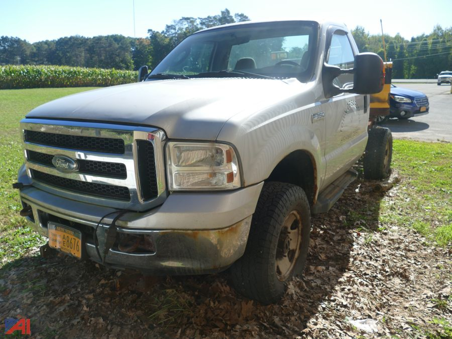 Ford F-350 Super Duty pickup with extended cab, single rear wheel, front grille and bumper, visible chrome trim, NY license plate, parked on leaves.