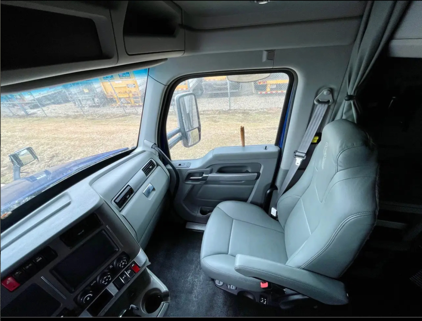 Truck cab interior view of a 2019 Kenworth T680 showing driver seat and dashboard with steering wheel, door panels, and window