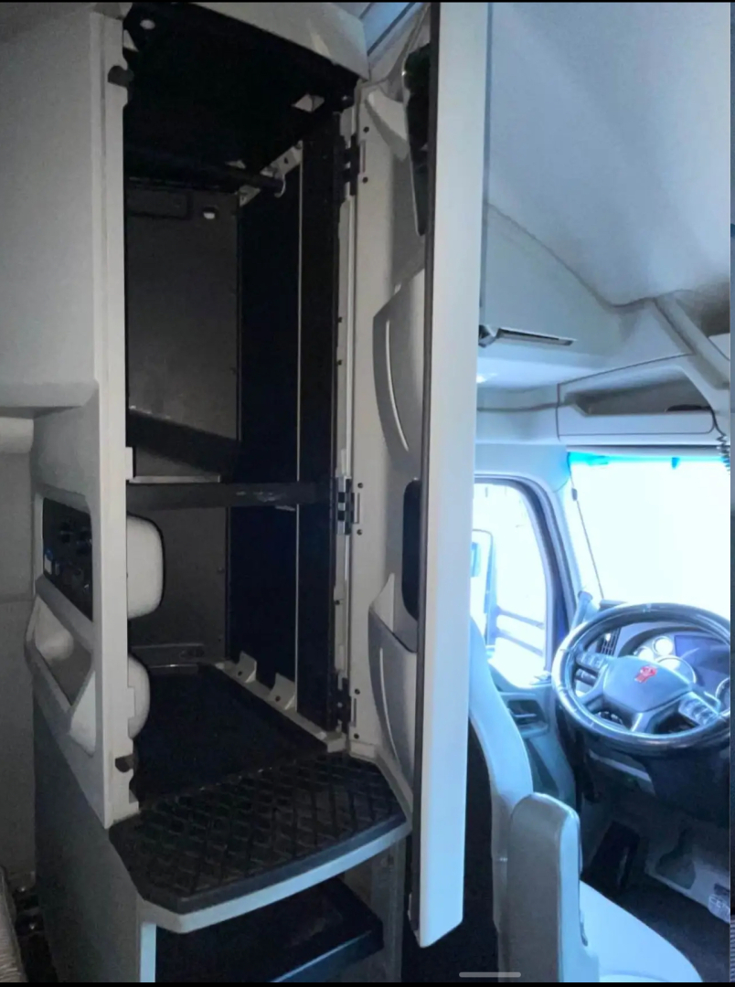 Kenworth T680 cab interior showing storage locker compartments and driver seat area.