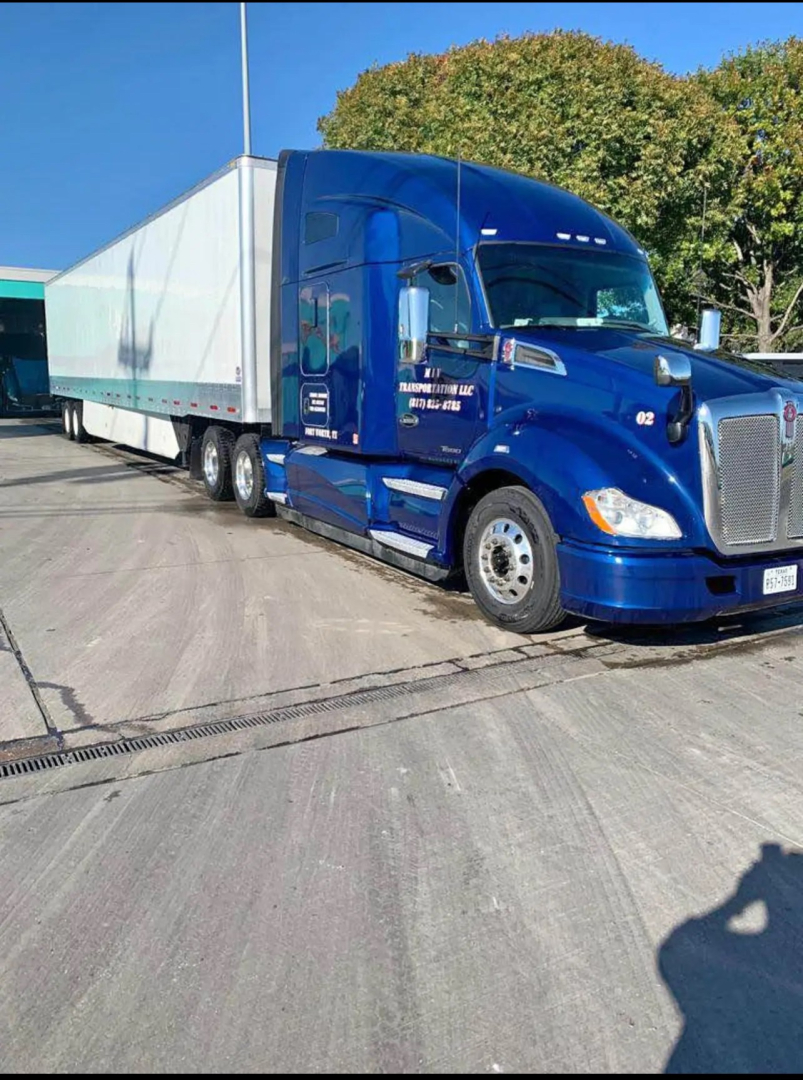 Kenworth T680 tractor with a blue cab and a long white trailer, side view showing front grille and wheels.