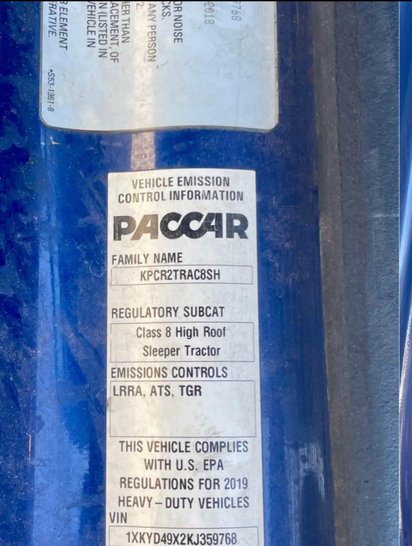 Vehicle emission control information sticker on Kenworth truck door. Text: VEHICLE EMISSION CONTROL INFORMATION PACCAR FAMILY NAME KPCR2TRACB8SH REGULATORY SUBCAT Class 8 High Roof Sleeper Tractor EMISSIONS CONTROLS LRRA, ATS, TGR THIS VEHI
