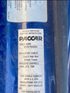 Vehicle emission control information sticker on Kenworth truck door. Text: VEHICLE EMISSION CONTROL INFORMATION PACCAR FAMILY NAME KPCR2TRACB8SH REGULATORY SUBCAT Class 8 High Roof Sleeper Tractor EMISSIONS CONTROLS LRRA, ATS, TGR THIS VEHI