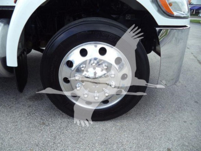 Front wheel and tire of a 2022 Peterbilt 337 rollback truck showing polished steel wheel and hubcap with bolts.