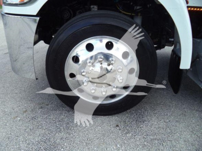 Peterbilt 337 wheel hub and front fender area showing chrome hubcap and black tire, partial white fender, truck components visible.
