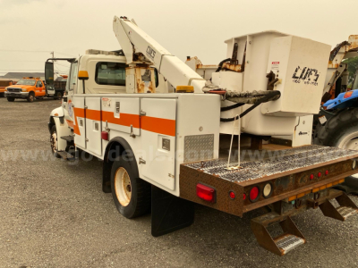 2007 International 4300 bucket truck with aerial lift, side view showing utility compartments and rear platform.