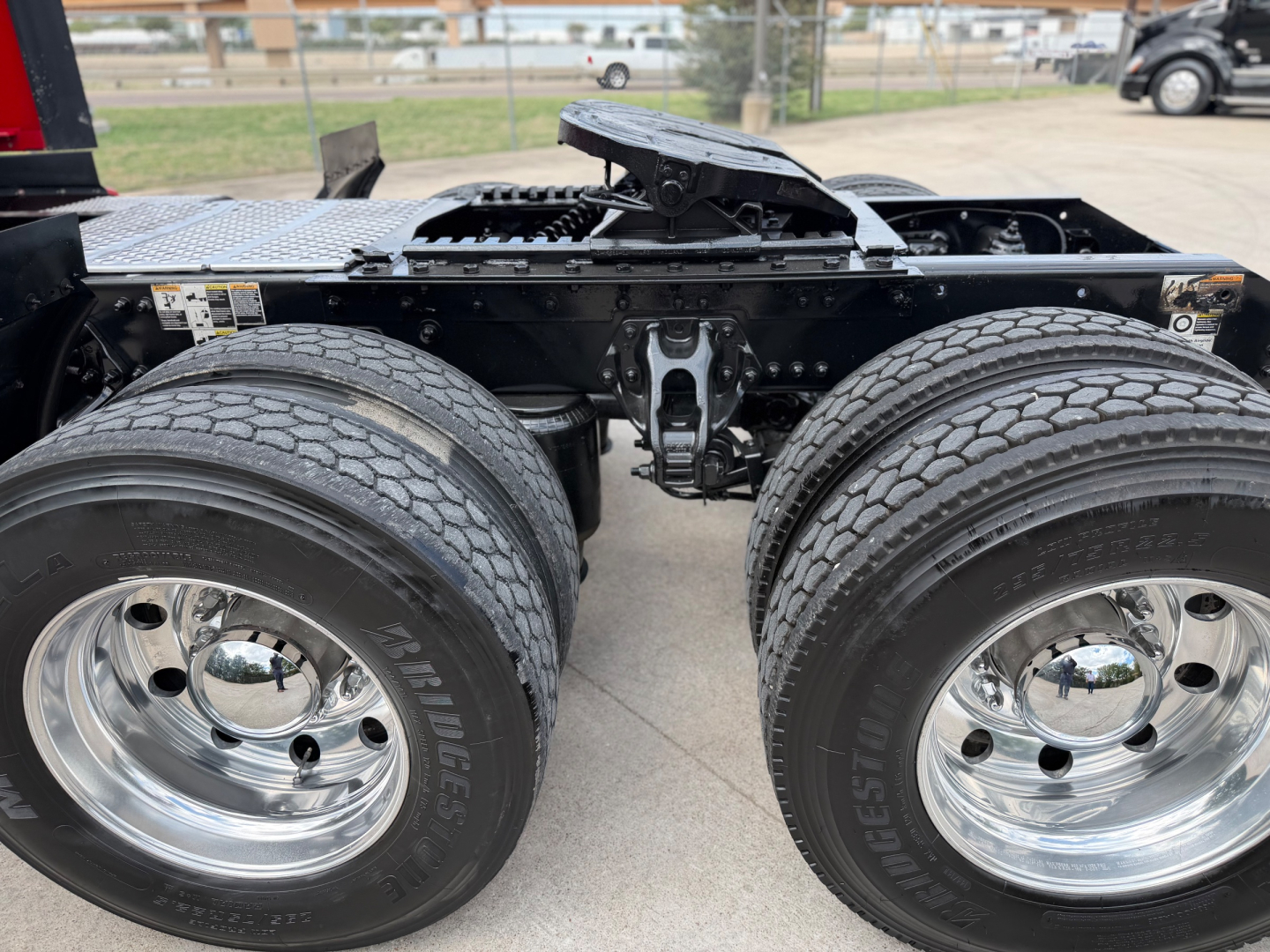 Kenworth T680 chassis with dual rear axles and chrome wheels, view of drive tires and seventh wheel area, no visible text.