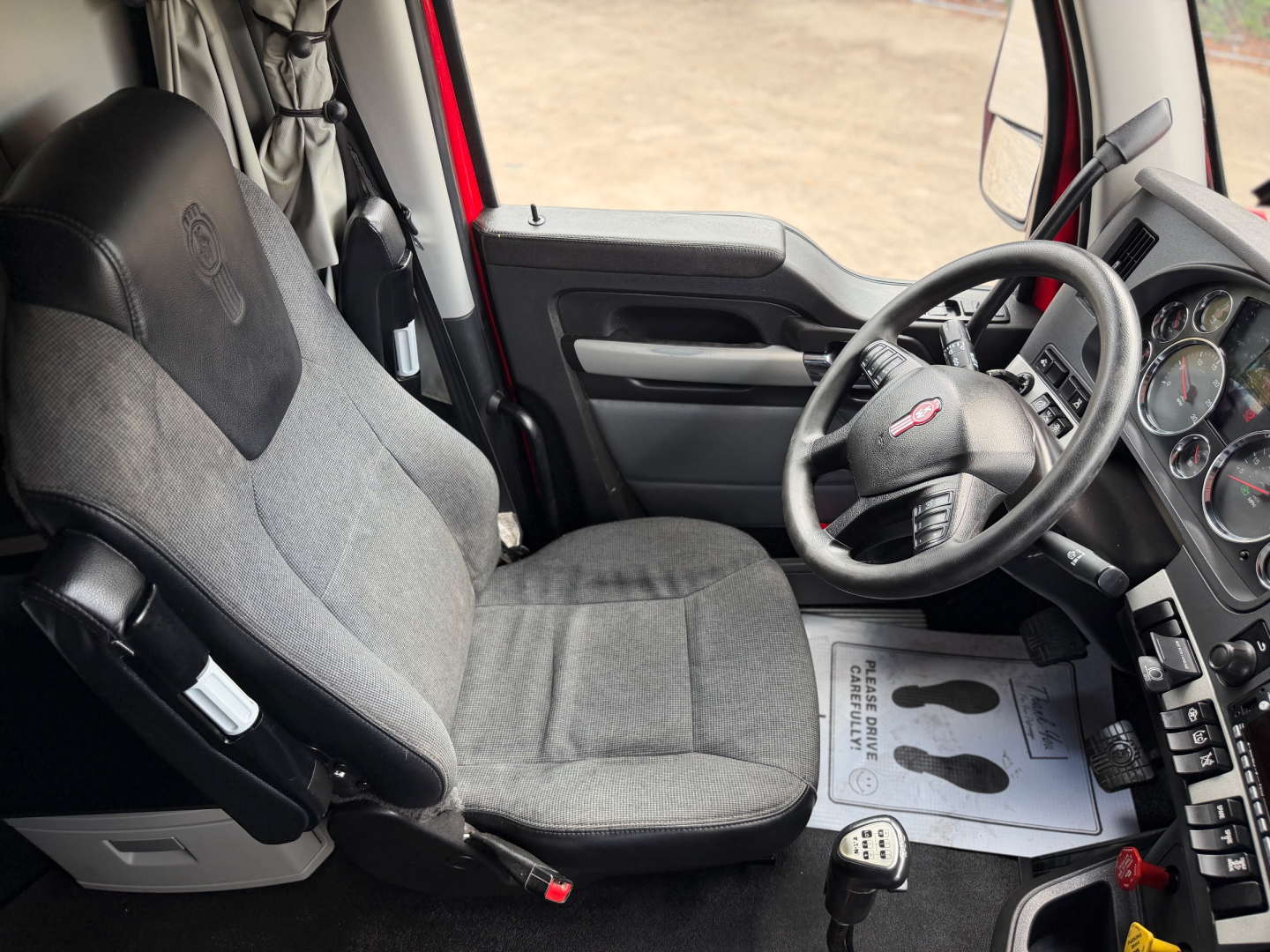Kenworth T680 truck interior showing driver seat and steering wheel with dashboard gauges and floor mats.