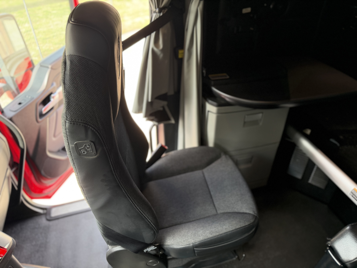 Kenworth T680 truck interior seat and cabin area view showing driver seat and part of dashboard and door frame.