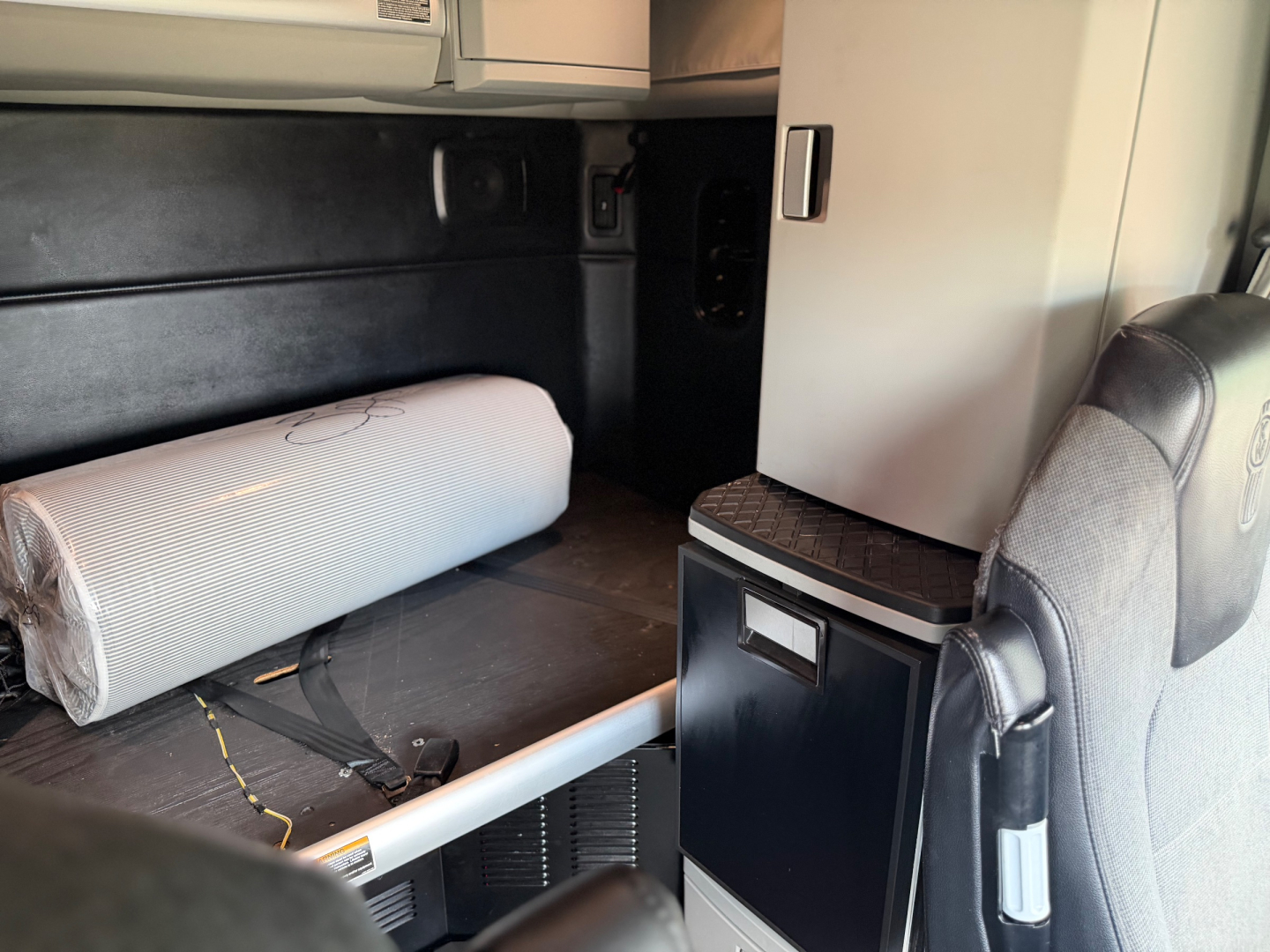 Kenworth T680 interior cargo area showing storage cabinet and sleeping berth with rolled mattress