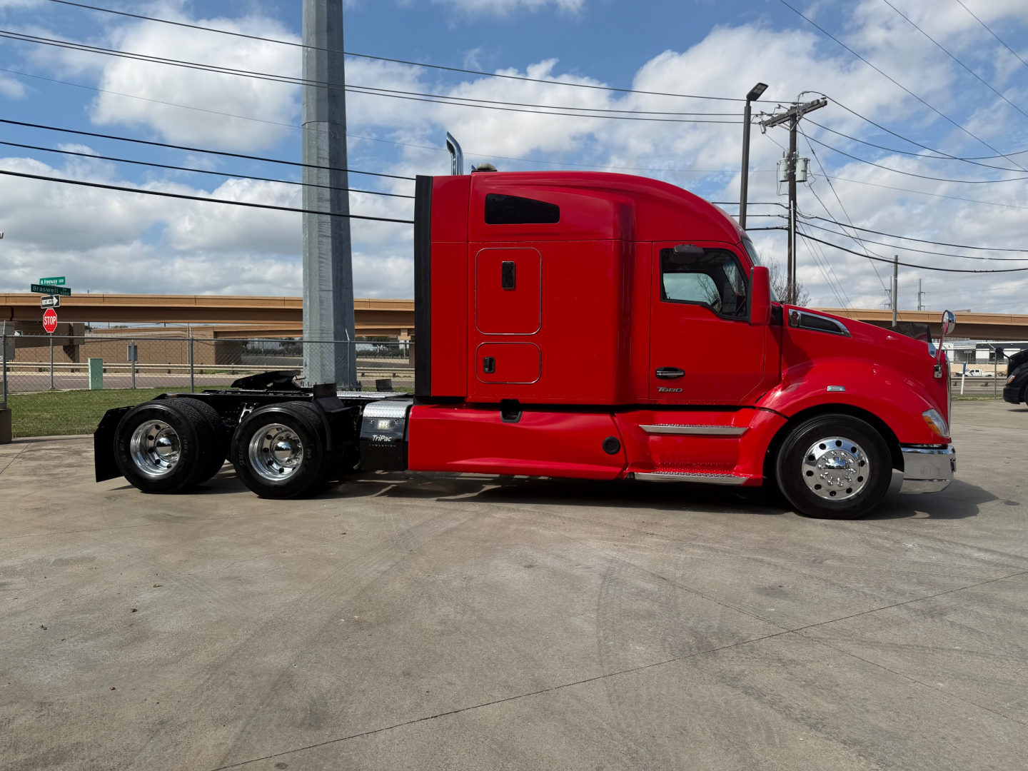 Kenworth T680 tractor in red, side view showing cab with sleeper, rear mudflaps, chrome wheels, and dual rear axles.