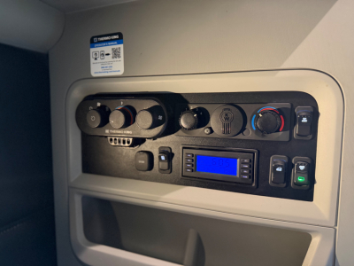 Kenworth T680 dash cluster showing climate controls, radio, and blue digital display in cabin view, with USB and switch panel.