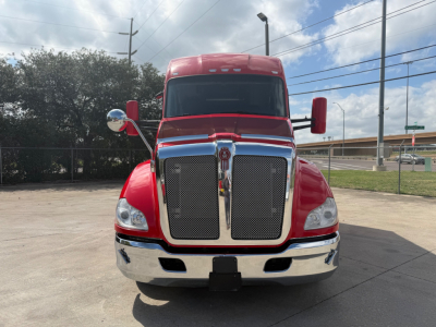 Kenworth T680 front view showing large chrome grille, red paint, dual hood mirrors, and bumper with license plate area.