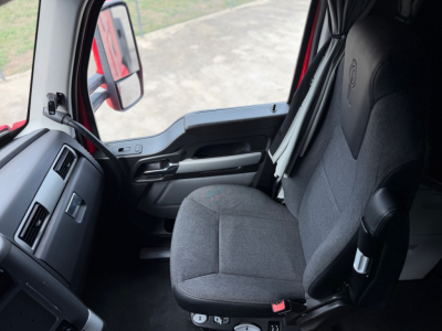 Kenworth T680 interior driver seat and dashboard view in cab with grey fabric seat and controls visible.