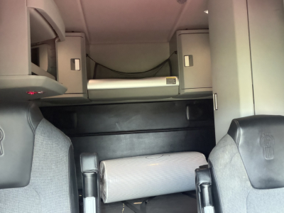 Kenworth T680 sleeper cab interior showing overhead storage shelves and a rolled bed bolster.