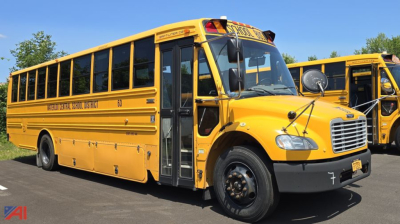 Yellow Freightliner Thomas B2 C2 school bus with front view, side lettering, black hub wheels, and a stop sign arm partially visible.
