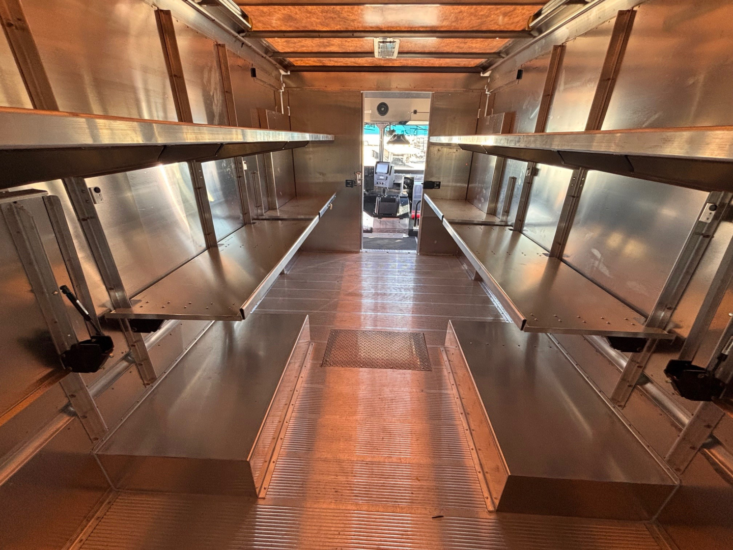 Interior of a new Harbinger S534 step van cargo area with metal shelving on both sides; view toward cab door at far end.