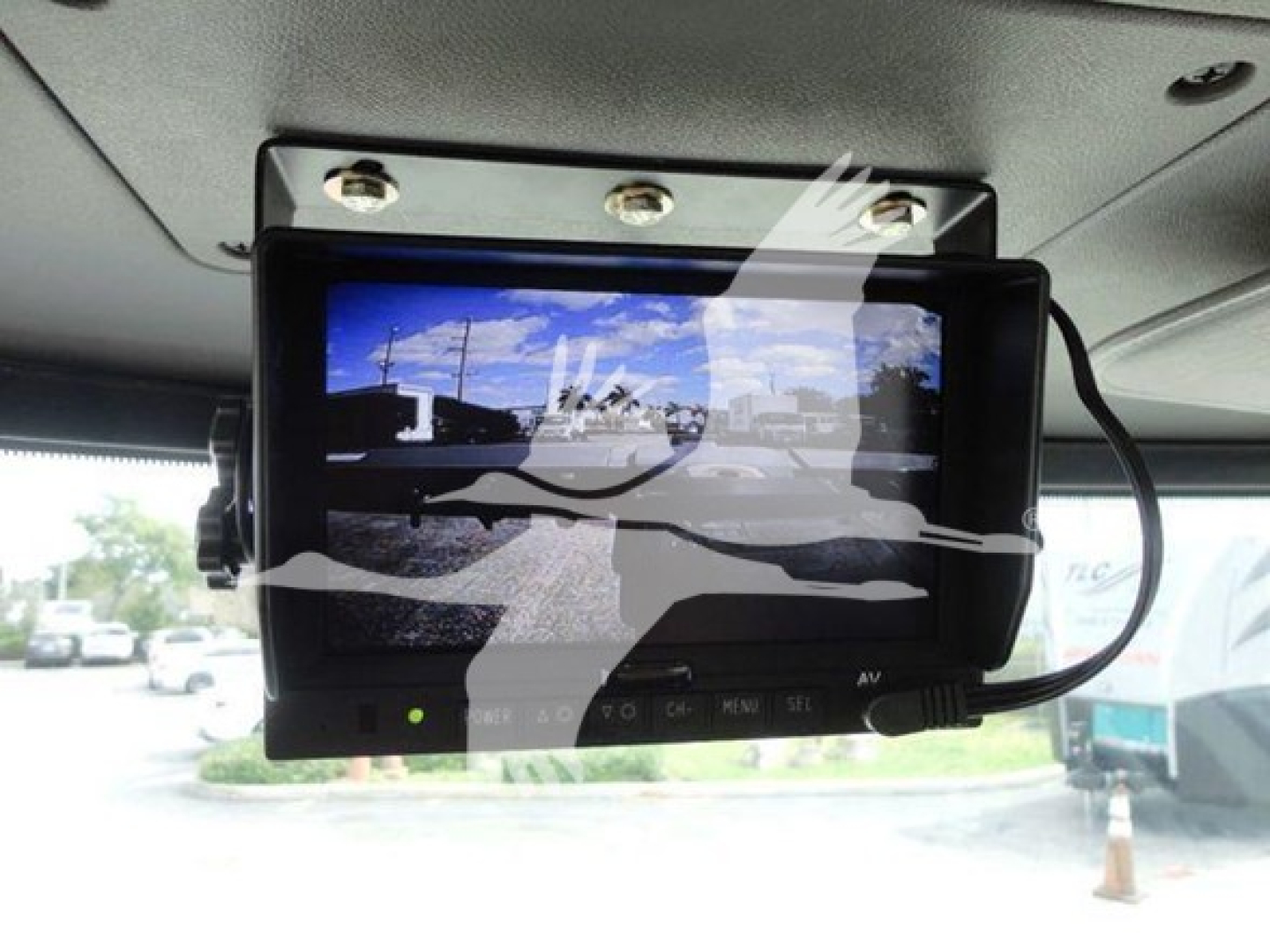 In-vehicle monitor mounted on Peterbilt interior showing blue sky and road; dashboard controls visible.