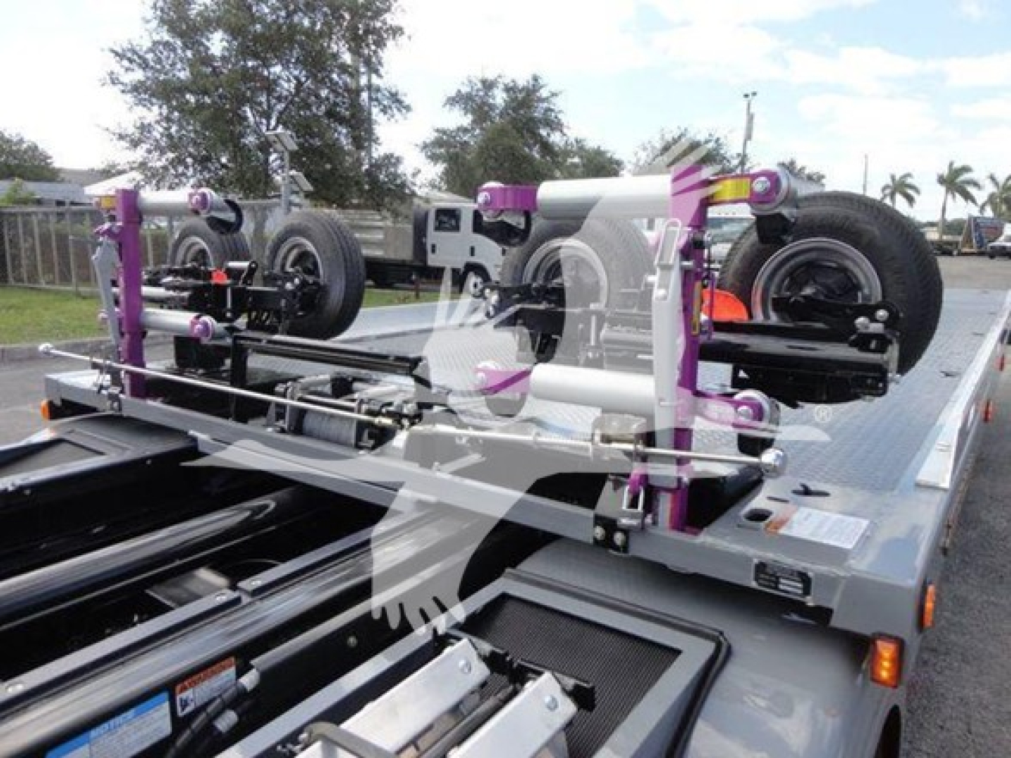 Truck bed with carrier system and purple accents showing the undercarriage and hoist components on a rollback truck.