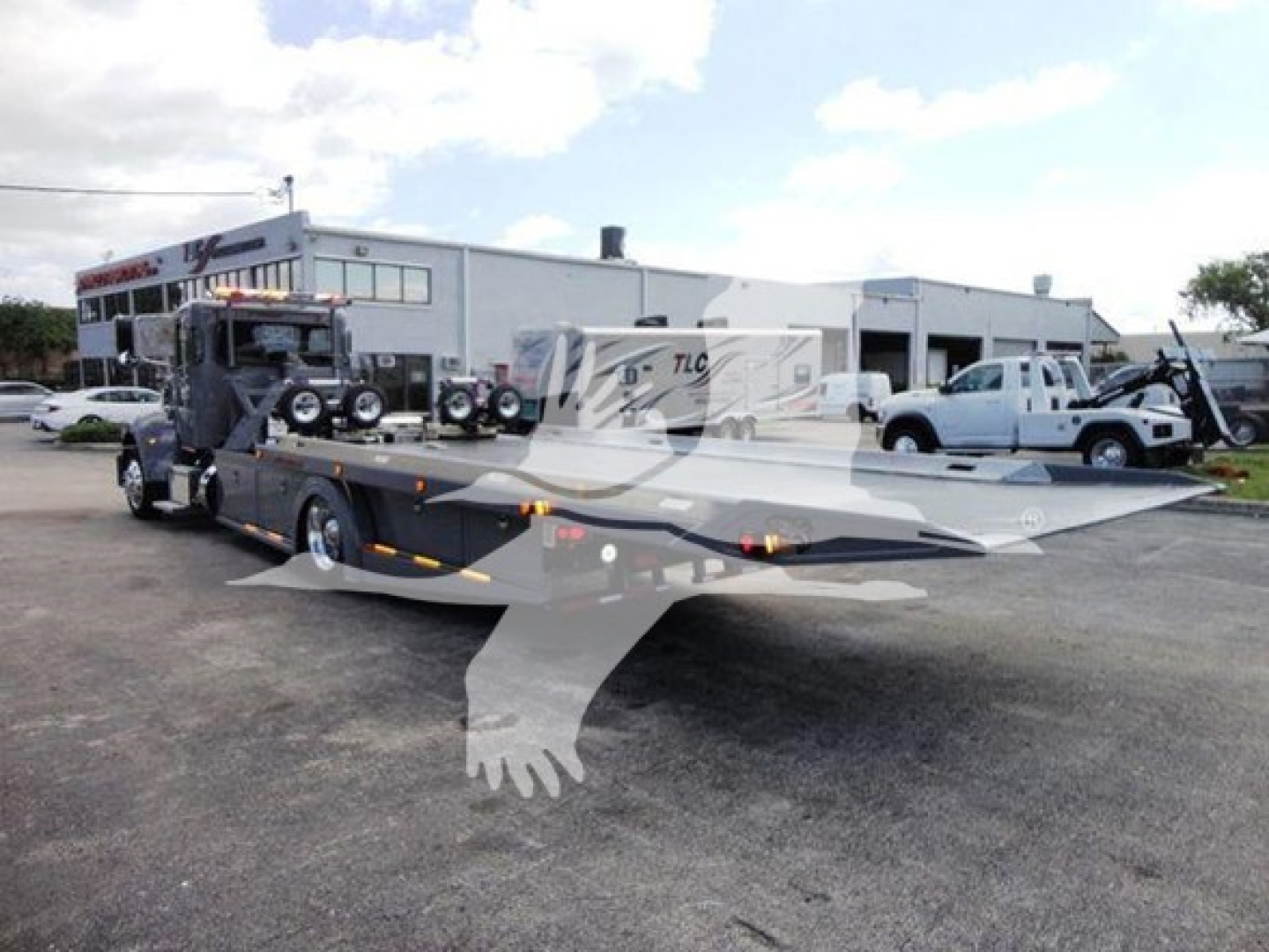 Peterbilt 337 rollback truck in a dealership lot with a car carrier bed.