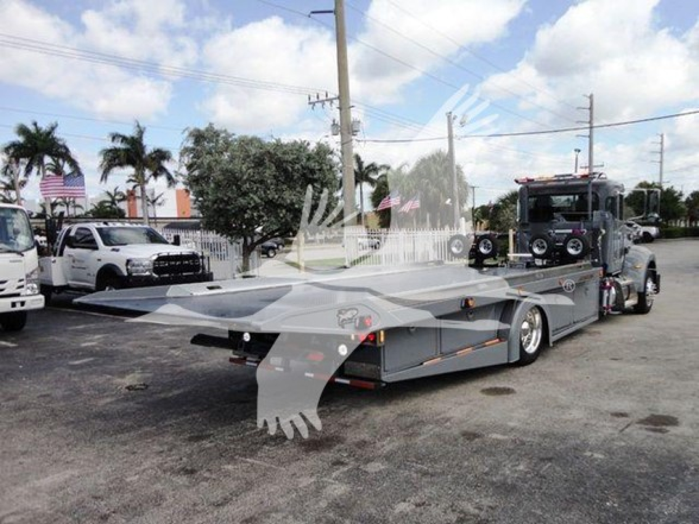 Peterbilt 337 rollback truck in lot with flatbed deck and towing cab.
