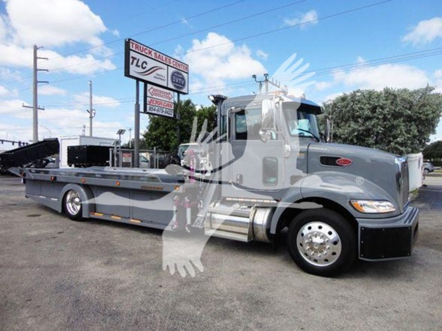 Peterbilt 337 rollback truck exterior side view showing gray cab and flatbed trailer with chrome wheels and branding.