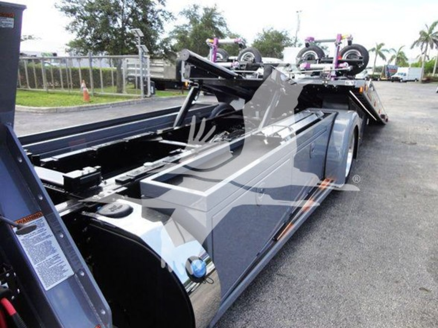 Peterbilt 337 rollback truck bed with hydraulic hoist and storage compartments, side view showing chrome accents and pump system.