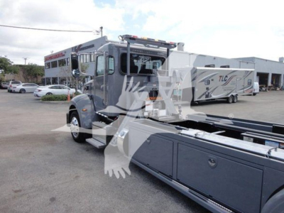 Truck cab of a 2022 Peterbilt 337 rollback w/ attached utility body and crane, side view showing chrome mirrors and storage compartments.