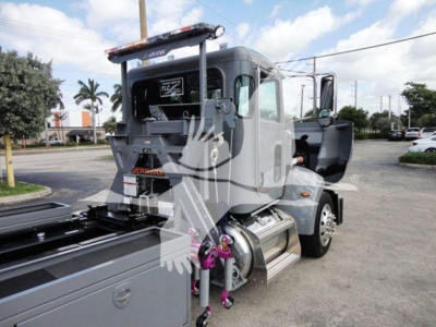 Peterbilt 337 rollback truck with open cab door showing side view, gray color, hauling equipment and dual fuel tanks.